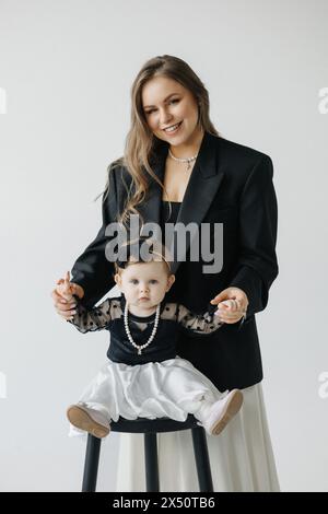 A happy woman is holding a smiling baby girl in black and white outerwear Stock Photo