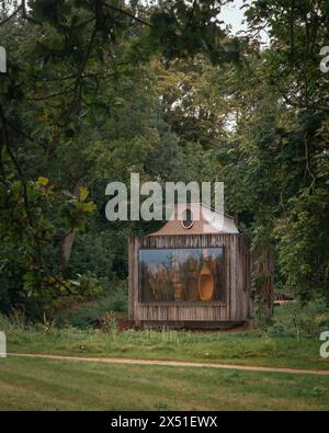 The Beezantium, surrounded by trees, seen across a field from behind. Large window and hives visible. The Beezantium at The Newt, Bruton, United Kingd Stock Photo