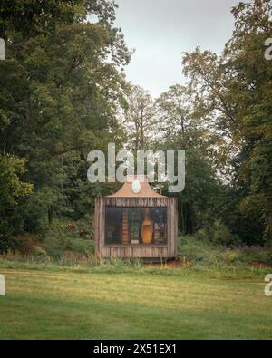 The Beezantium, surrounded by trees, seen across a field from behind. Large window and hives visible. The Beezantium at The Newt, Bruton, United Kingd Stock Photo