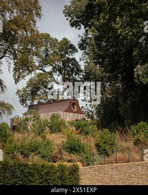 The Apiary Pavilion Surrounded by trees and landscaping with Bath stone wall in foreground. The Beezantium at The Newt, Bruton, United Kingdom. Archit Stock Photo