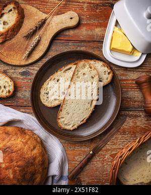 Freshly baked bread with butter on a rustic kitchen table setup, top view Stock Photo