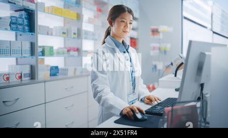 Pharmacy Drugstore: Beautiful Asian Pharmacist Uses Checkout Counter Computer, Does Inventory Checkup, Online Prescription of Medicine Packages, Drugs, Vitamin Boxes, Supplements, Health Care Products Stock Photo