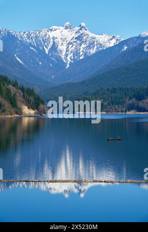 Capilano Lake Lions Peaks Reflection North Vancouver vertical. The view of the Lions high over the Capilano Lake Reservoir in Capilano River Regional Stock Photo