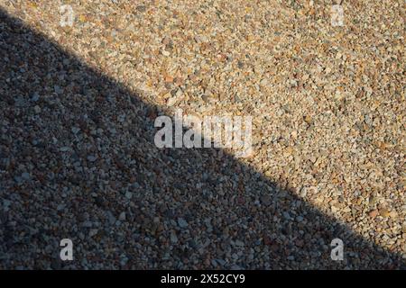 A close-up of small, multicolored pebbles overlaid with contrasting diagonal shadows, creating a dynamic and textured background suitable for artistic Stock Photo