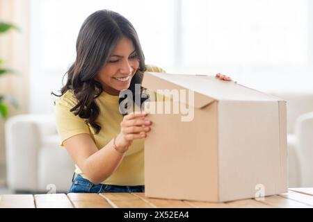 Excited Woman Opening a Box on a Table Stock Photo