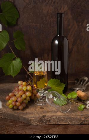 The concept of a delicious alcoholic drink, wine and grapes. Wine bottle, cork, corkscrew, empty glass and glass of white wine and bunch of pink grape Stock Photo