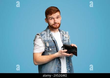 Sad millennial man showing his empty wallet to camera Stock Photo