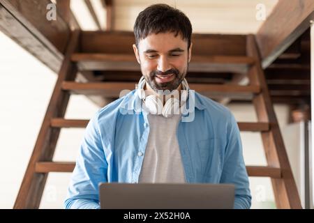 Man Using Laptop With Headphones, Sitting on Stairs Stock Photo
