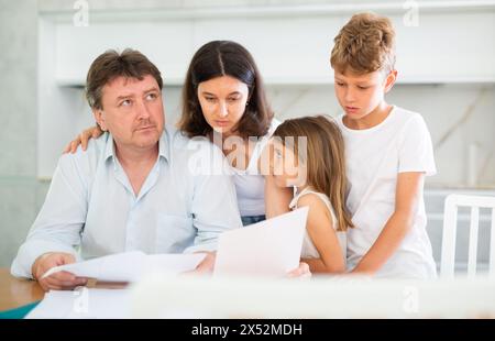 Wistful father looking through papers with family Stock Photo