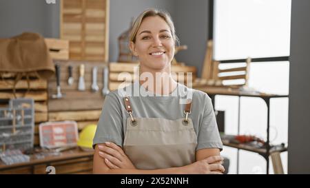 Confident woman carpenter standing in workshop with arms crossed Stock Photo