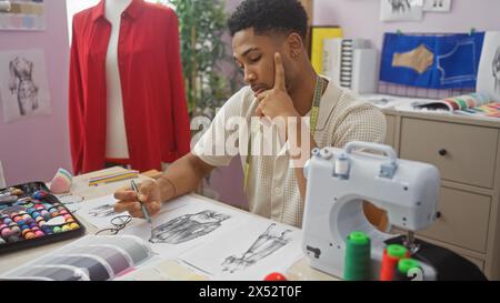 An african american man sketches fashion designs in a colorful tailor shop, surrounded by sewing equipment and fabric samples. Stock Photo