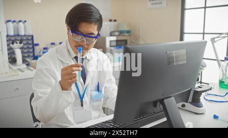 A young asian man analyzing a test tube in a modern laboratory setting, embodying professionalism and focused research. Stock Photo