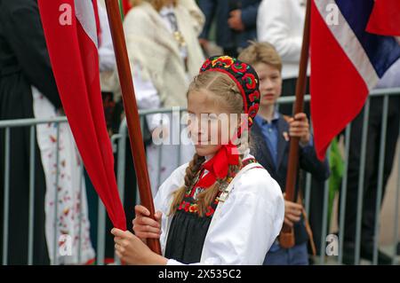 Young girl in old traditional costume walking on the streets waving flags, folklore, bank holidays 17 May, Norwegian flag, Oslo, Norway Stock Photo