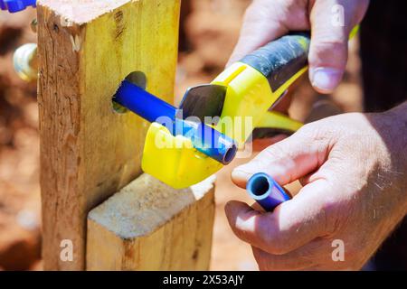 Plumber cutting blue plastic PVC water piping using saw tool Stock Photo