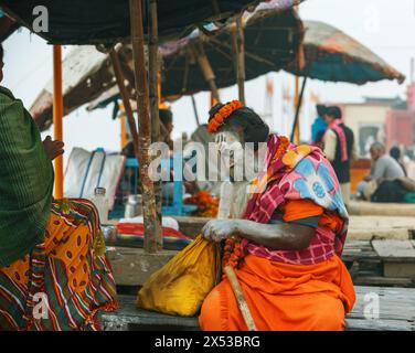 Brightly dressed sadhu or spiritual aspirant  sitting on a puja platform in Varanasi, India. Stock Photo