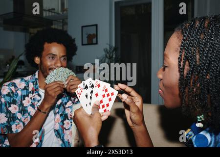 Young Black couple playing cards at home in the evening Stock Photo