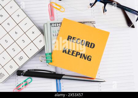 Record keeping text concept on a yellow sticker with money on a business notebook Stock Photo