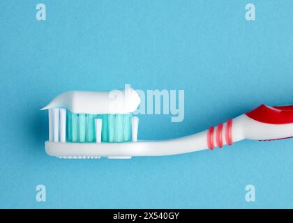 Macro close up view of a plastic toothbrush with toothpaste on blue background. Dental care and hygiene concept. Stock Photo