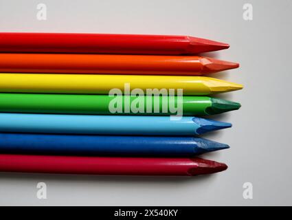 Photo of colored pencils arranged in the colors of the rainbow on white background. Pencils without wood. Pencils are placed in the middle, horizontal Stock Photo