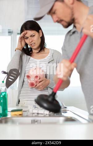 cleaning clogged pipes in the kitchen sink with a plunger Stock Photo