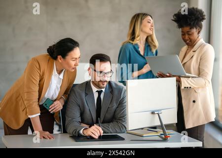 Senior business manager talking with experienced colleague while using computer in office. Stock Photo