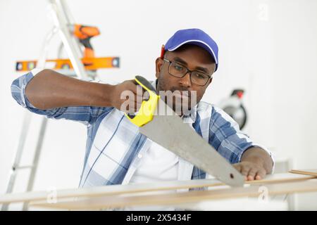 a man carpenter cuts a wooden beam Stock Photo