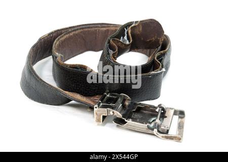 Used and Old black leather belt with buckle isolated on white background. Aged rolled-up black leather belt with a metal buckle. Stock Photo