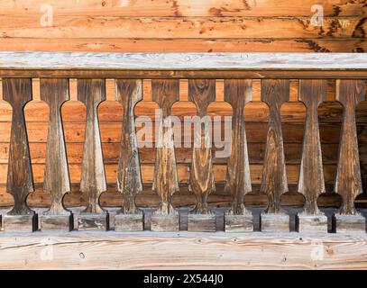 Wooden balustrade against the background of a wooden wall. The structure is wooden. Background Stock Photo