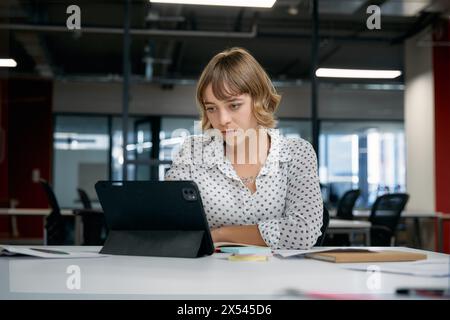 Focused young caucasian businesswoman using digital tablet during meeting in office Stock Photo
