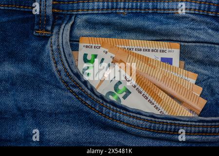Three folded 50 Euro banknote bills stuck in front pocket of blue jeans Stock Photo