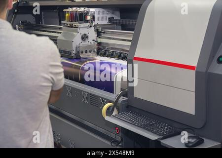 Modern printing machine and worker near it. iIdustry Stock Photo