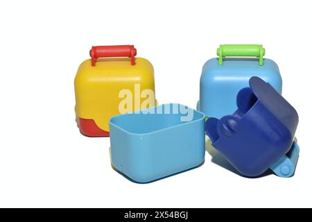 Children's toy chests made of plastic, painted in different bright colors, lie on a white background. Stock Photo