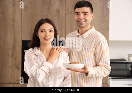 Happy young couple having breakfast in kitchen Stock Photo