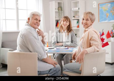 Mature couple with travel agent sitting at table in office Stock Photo