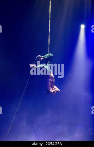 The American acrobat Nick Hodge hangs upside down and unsecured from a rope while performing in 'Avalon', the 2024 Giffords Circus show (UK) Stock Photo