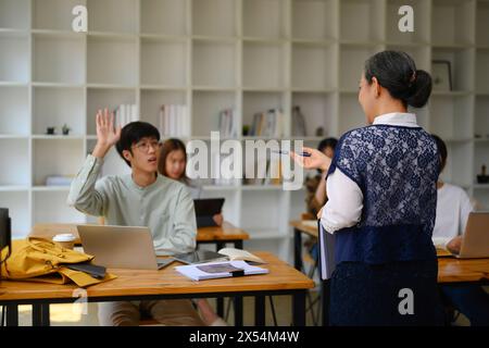 College student man raising his hand to answer question or ask something during class Stock Photo