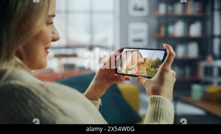 Close Up of a Female Chatting in a Video Call with Her Beautiful Friend Playing with a Dog on Smartphone from Home Living Room. Freelancer Chatting with a Client on a Call Over the Internet. Stock Photo