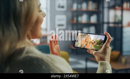 Close Up of a Female Chatting in a Video Call with Her Beautiful Friend Playing with a Dog on Smartphone from Home Living Room. Freelancer Chatting with a Client on a Call Over the Internet. Stock Photo