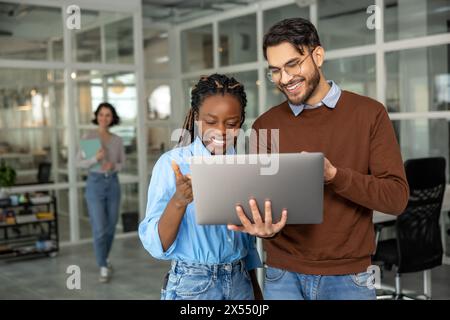 Diverse colleagues collaborating on project together using laptop Stock Photo