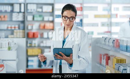 Pharmacy Drugstore: Beautiful Caucasian Pharmacist Uses Digital Tablet Computer, Checks Inventory of Medicine, Drugs, Vitamins, Health Care Products on a Shelf. Professional Pharmacist in Pharma Store Stock Photo