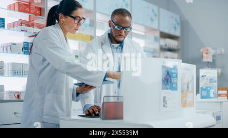 Pharmacy: Black Male and Caucasian Female Pharmacists Use Digital Tablet Computer Talk about Medicine, Drugs, Vitamins, Supplements, Vaccine, Health Care Products. Medical Professionals in Drugstore Stock Photo