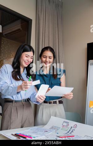 ux developer and ui designer presenting mobile app interface design on whiteboard in meeting at office. Creative digital development mobile app agency Stock Photo