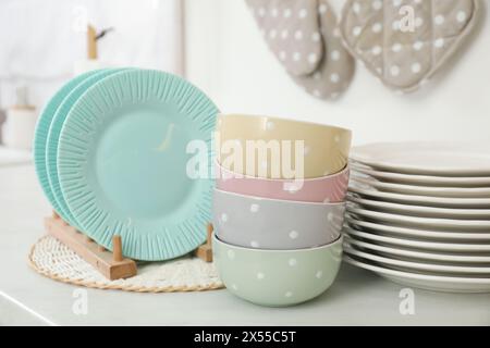 Clean plates and bowls on white countertop in kitchen Stock Photo