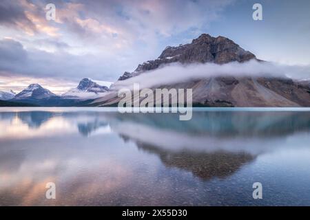 Crow Mountain reflected in the mirror still waters of Bow Lake at dawn in the Canadian Rockies, Banff National Park, Alberta, Canada. Stock Photo