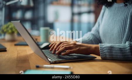 Close Up on Hands of a Female Specialist Working on Laptop Computer at Cozy Home Living Room while Sitting at a Table. Freelancer Woman Chatting Over the Internet on Social Networks. Stock Photo
