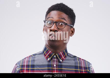 Black man, glasses and portrait in studio for surprise, gossip and pout on white background. Shocked, comic and male person with spectacles for nerd Stock Photo