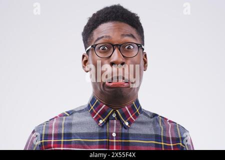 Black man, funny face or portrait with glasses in studio for comic, comedy and silly expression by white background. Male person, goofy or weird with Stock Photo