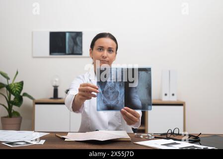 doctor telemedicine consultation, pointing at X-ray film explaining to patient , looking to camera. Stock Photo