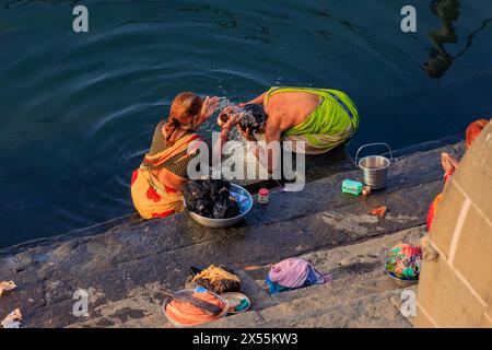 two indian women in colourful saris stand in river narmada on the maheshwar ghats washing their hair Stock Photo