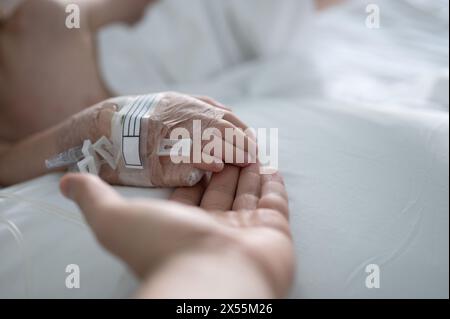 Helping kid recover after illness in  hospital holding his hand with iv Stock Photo